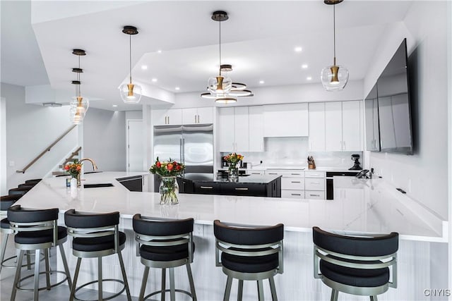 kitchen featuring white cabinetry, a large island with sink, stainless steel fridge, tasteful backsplash, and a sink