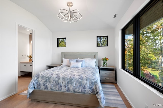 bedroom featuring ensuite bath, a notable chandelier, vaulted ceiling, and light hardwood / wood-style floors