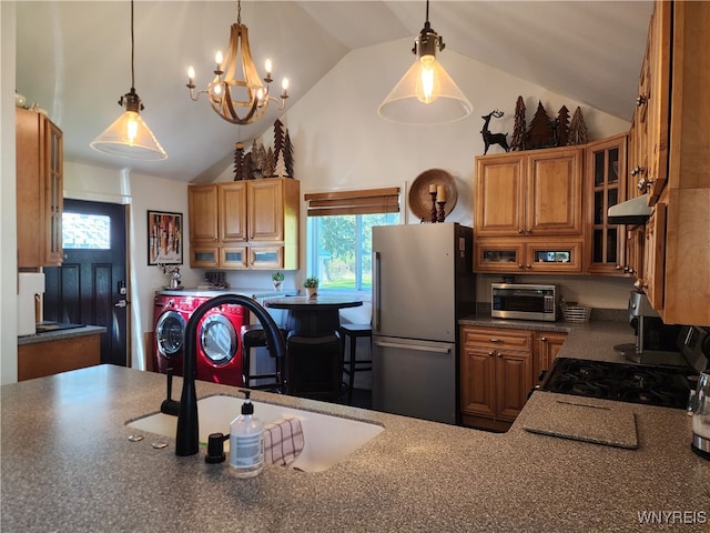 kitchen featuring hanging light fixtures, ventilation hood, a notable chandelier, washing machine and clothes dryer, and stainless steel refrigerator