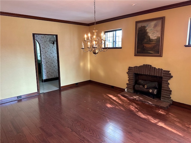 unfurnished living room with a notable chandelier, ornamental molding, dark wood-type flooring, and a brick fireplace