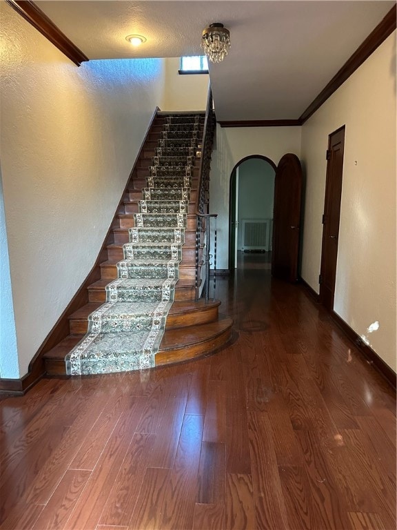 staircase with ornamental molding and hardwood / wood-style floors