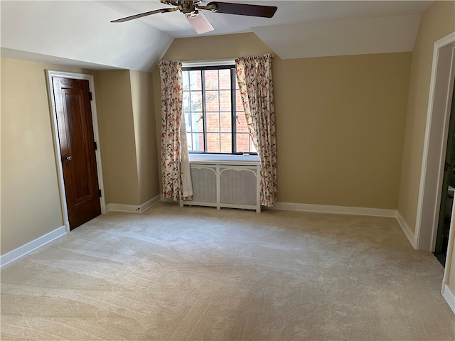 interior space with radiator heating unit, ceiling fan, light colored carpet, and vaulted ceiling