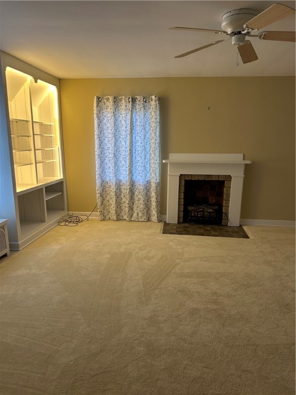 unfurnished living room with a tiled fireplace, carpet flooring, and ceiling fan