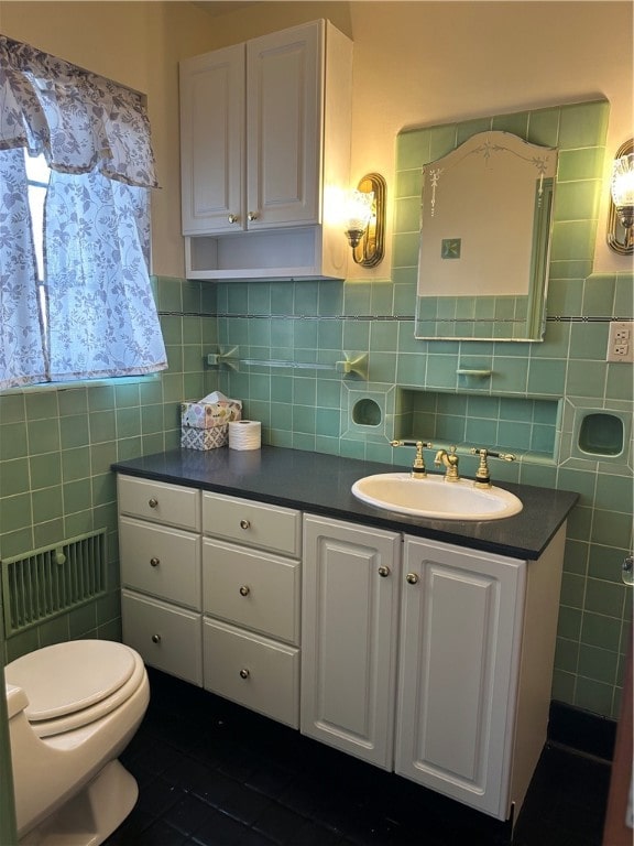 bathroom featuring vanity, toilet, and tile walls