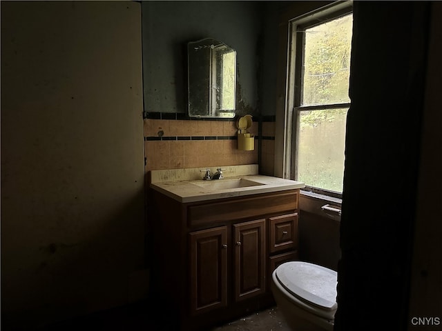 bathroom featuring vanity, toilet, and tile walls