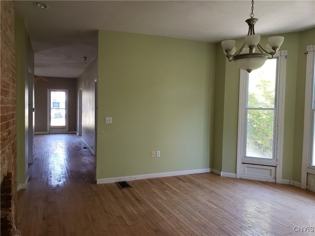 empty room featuring a chandelier and hardwood / wood-style flooring