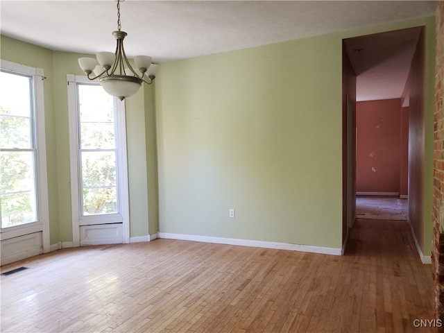 empty room featuring light hardwood / wood-style floors and a notable chandelier