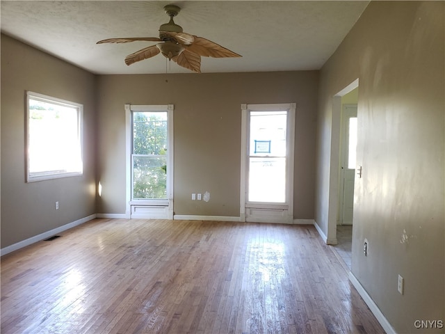 empty room with ceiling fan, light hardwood / wood-style flooring, and plenty of natural light