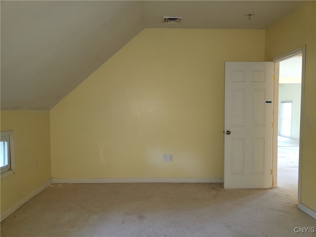 additional living space featuring lofted ceiling, light carpet, and plenty of natural light