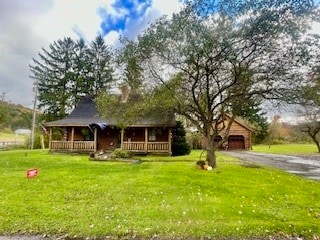 view of front of property featuring covered porch, a front lawn, and a garage