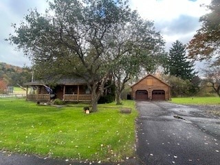 view of front of house featuring a porch, a front yard, an outbuilding, and a garage