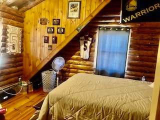 bedroom with rustic walls and hardwood / wood-style floors