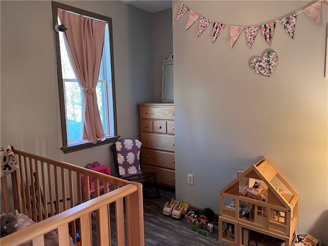 bedroom featuring a nursery area and dark hardwood / wood-style floors