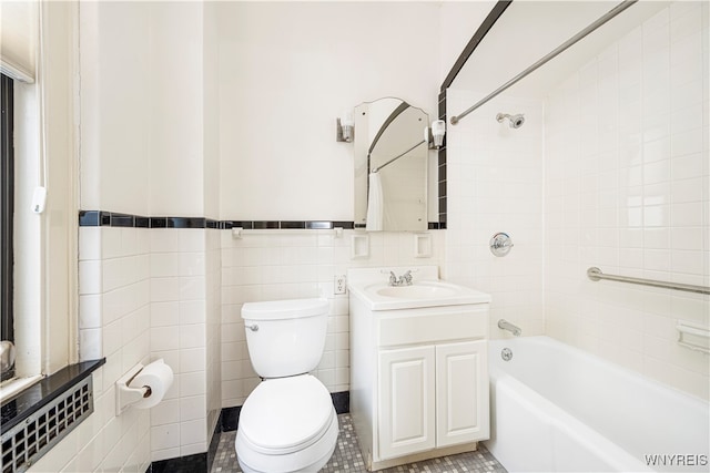 full bathroom with toilet, tile patterned flooring, vanity, tiled shower / bath combo, and tile walls