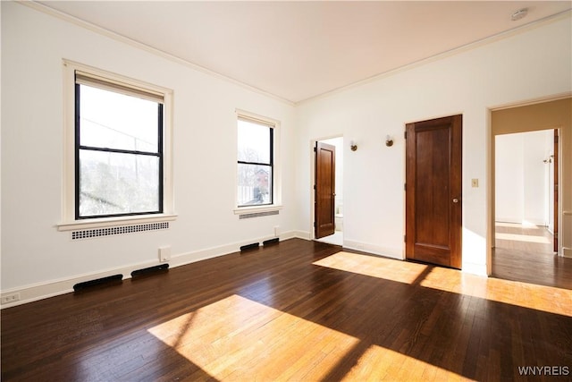 spare room featuring ornamental molding, wood finished floors, and baseboards