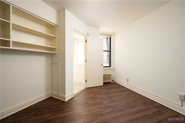 unfurnished bedroom with radiator and dark wood-type flooring