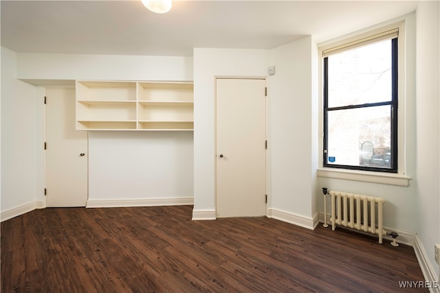 unfurnished bedroom featuring radiator heating unit and dark hardwood / wood-style floors