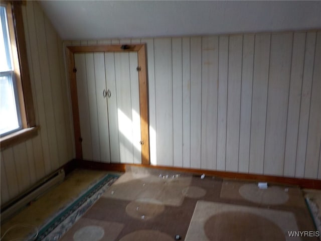 interior space with wooden walls and a baseboard heating unit