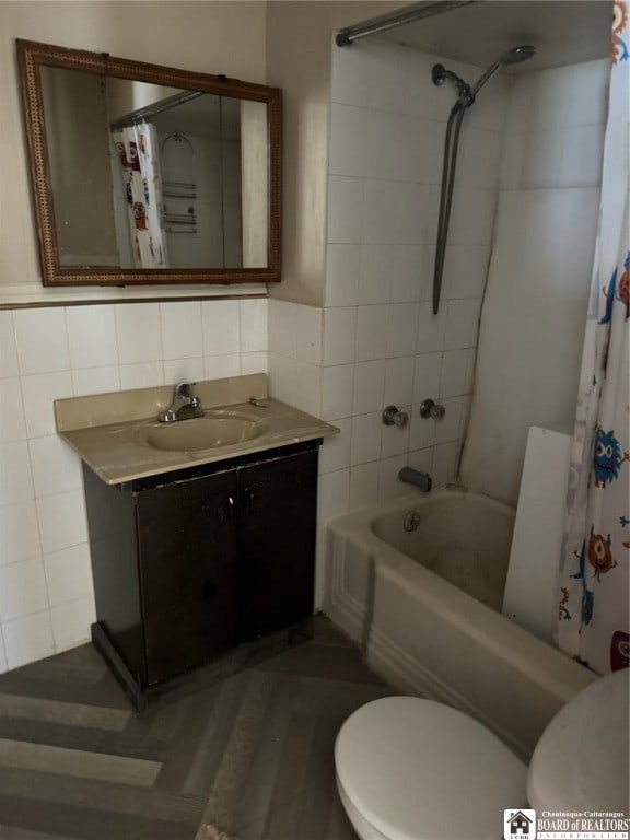 full bathroom featuring toilet, shower / bath combo with shower curtain, vanity, and tile walls