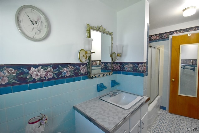 bathroom featuring vanity, tile patterned flooring, combined bath / shower with glass door, and tile walls