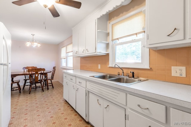 kitchen with tasteful backsplash, sink, pendant lighting, white cabinets, and white refrigerator