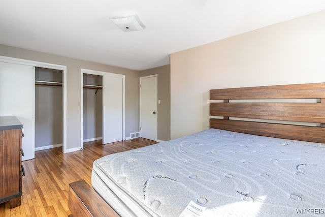 bedroom featuring two closets and light wood-type flooring