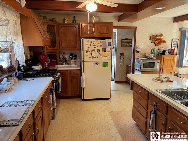 kitchen featuring beamed ceiling, a healthy amount of sunlight, stainless steel appliances, and ceiling fan