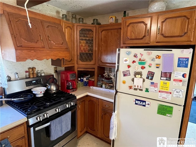 kitchen with stainless steel range with gas stovetop and white refrigerator