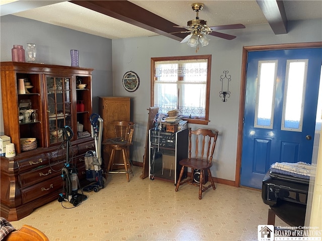 sitting room featuring ceiling fan and beamed ceiling