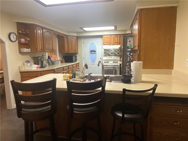 kitchen with stove, a kitchen breakfast bar, kitchen peninsula, and stainless steel refrigerator