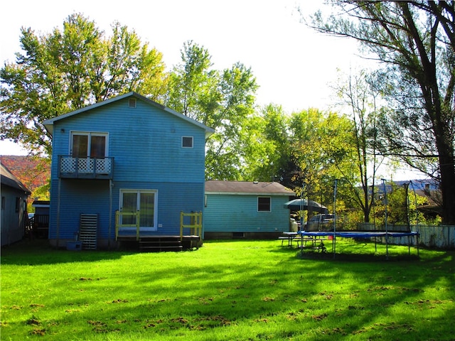 back of property with a trampoline and a lawn