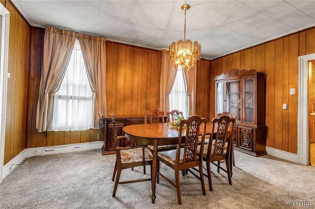 carpeted dining area with crown molding, a notable chandelier, and wood walls