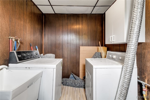 washroom with washer and dryer, cabinets, and wood walls