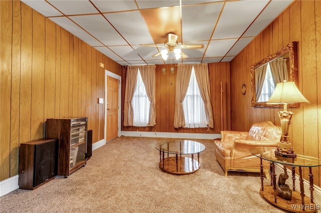 sitting room with wood walls, carpet, and ceiling fan