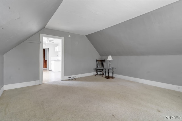 additional living space with lofted ceiling, light carpet, and ceiling fan