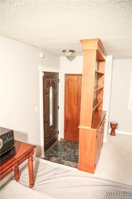 carpeted foyer entrance with a textured ceiling