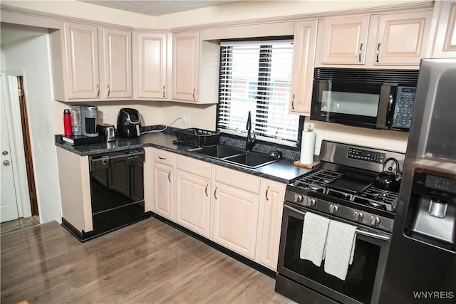 kitchen featuring a textured ceiling, hardwood / wood-style flooring, black appliances, and sink