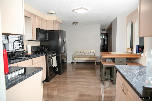 kitchen with high end stove, cream cabinetry, light hardwood / wood-style flooring, sink, and a textured ceiling