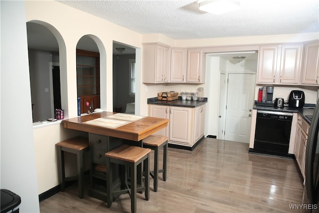 kitchen with light hardwood / wood-style floors, a textured ceiling, dishwasher, and cream cabinetry