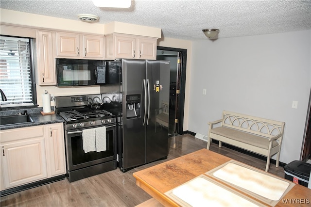 kitchen with appliances with stainless steel finishes, a textured ceiling, hardwood / wood-style flooring, and sink