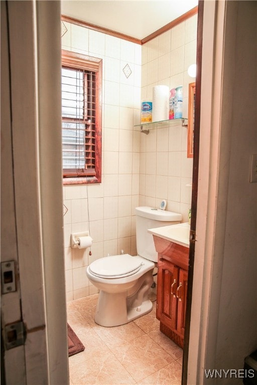 bathroom featuring tile patterned floors, toilet, vanity, ornamental molding, and tile walls