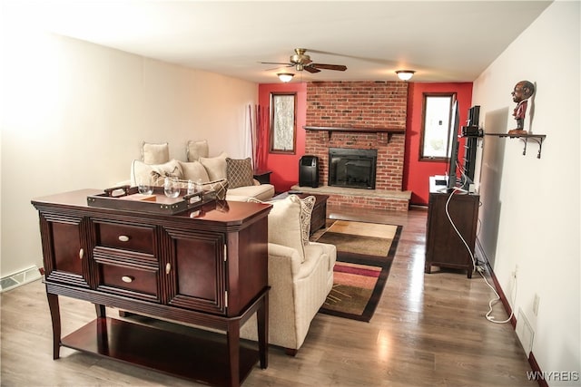 living room featuring a fireplace, wood-type flooring, and ceiling fan