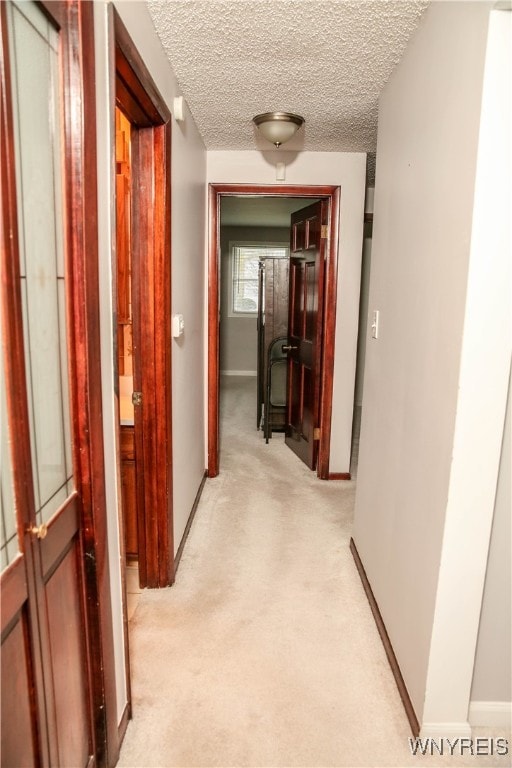 corridor featuring light carpet and a textured ceiling