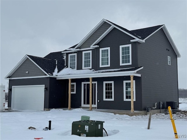 view of front of home with an attached garage, a porch, and central AC