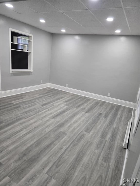 basement with a drop ceiling, hardwood / wood-style flooring, and built in features