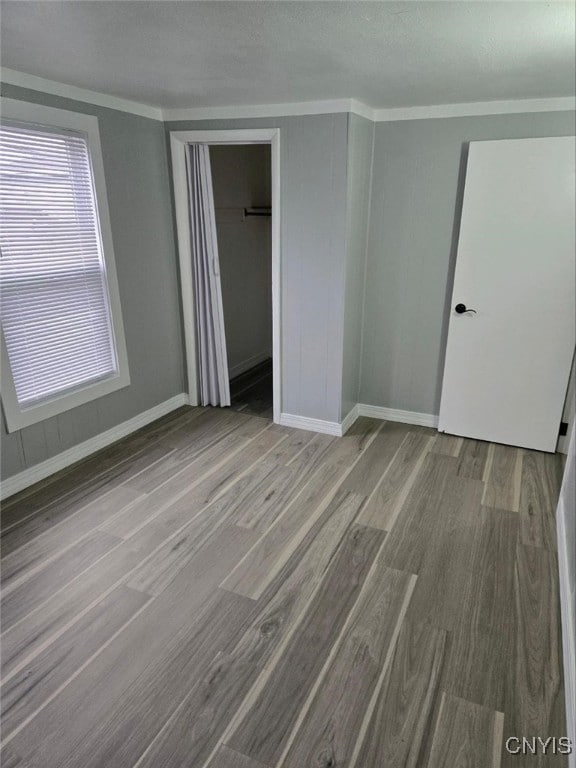 unfurnished bedroom featuring a closet, crown molding, a textured ceiling, and light wood-type flooring