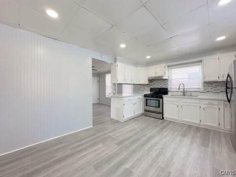 kitchen with tasteful backsplash, appliances with stainless steel finishes, light hardwood / wood-style floors, and white cabinets