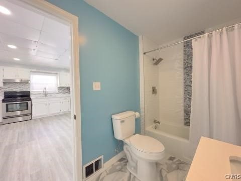 full bathroom featuring shower / tub combo, sink, backsplash, and toilet