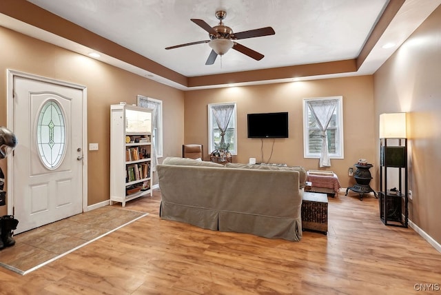 living room featuring a tray ceiling, light hardwood / wood-style floors, and ceiling fan