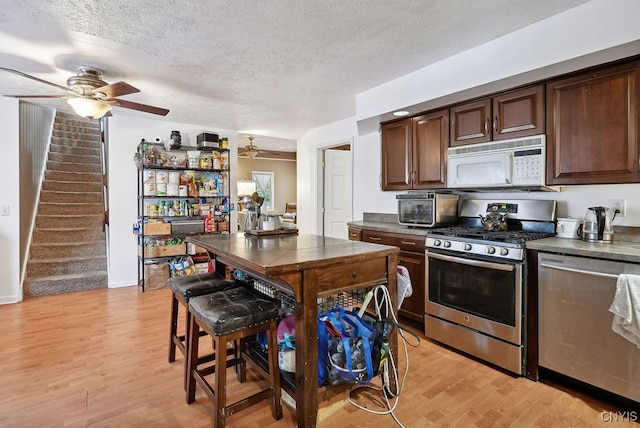 kitchen with dark brown cabinets, stainless steel appliances, a textured ceiling, light hardwood / wood-style floors, and ceiling fan